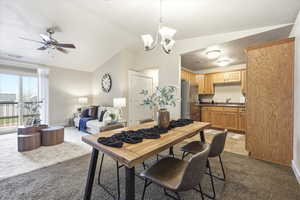 Dining room with light colored carpet, suspended lighting, lofted ceiling, and a ceiling fan