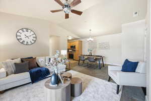 Living room featuring light colored carpet, ceiling fan, vaulted ceiling, and suspended lighting