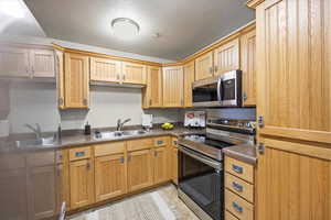 Kitchen with stainless steel appliances, dark countertops, a textured ceiling, and light tile patterned floors