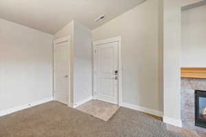 Entryway with lofted ceiling, light colored carpet, and a tile fireplace