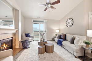 Living area with ceiling fan, a tiled fireplace, and vaulted ceiling