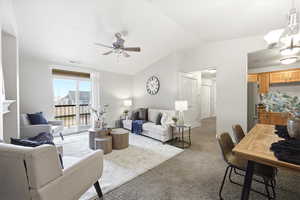 Carpeted living area featuring ceiling fan, vaulted ceiling, and a chandelier