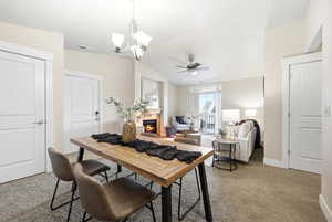 Office area featuring carpet flooring, lofted ceiling, a lit fireplace, ceiling fan, and suspended lighting
