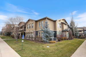View of front facade featuring stone siding, a front lawn, and board and batten siding