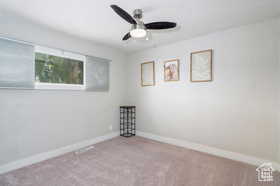 Carpeted empty room featuring baseboards and a ceiling fan