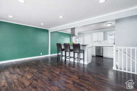Kitchen with white cabinets, a kitchen breakfast bar, dark wood finished floors, recessed lighting, and stainless steel dishwasher