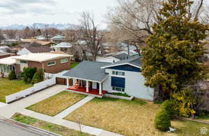 View of front facade featuring driveway, a residential view, covered porch, roof with shingles, and a mountain view