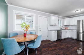 Kitchen with white cabinetry, appliances with stainless steel finishes, dark wood-style floors, and light countertops