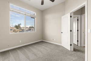 Carpeted spare room with baseboards and a ceiling fan