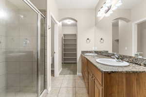 Bathroom featuring double vanity, light tile patterned flooring, a shower stall, and a spacious closet