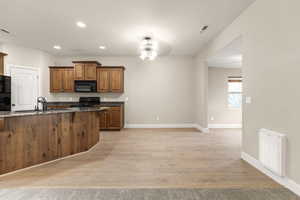 Kitchen featuring recessed lighting, dark stone countertops, black appliances, a ceiling fan, and light wood-style floors