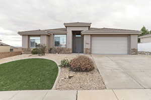 Prairie-style home featuring stone siding, stucco siding, driveway, a tiled roof, and an attached garage