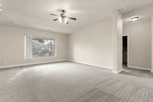Spare room featuring light colored carpet, ceiling fan, and vaulted ceiling
