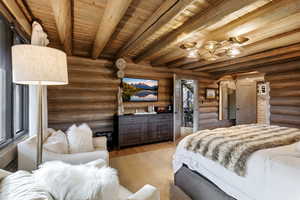 Bedroom with a wooden ceiling with exposed beams, rustic walls, arched walkways, and wood finished floors