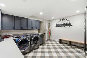 Washroom with washing machine and dryer, recessed lighting, light flooring, and cabinet space