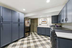 Kitchen with light floors, beverage cooler, gray cabinets, washer and clothes dryer, and recessed lighting