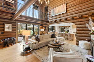 Living room featuring a towering ceiling, hardwood / wood-style flooring, a chandelier, and rustic walls