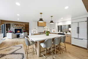 Kitchen featuring hanging light fixtures, a kitchen breakfast bar, light wood-style floors, a center island, and rustic walls