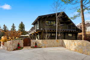 View of front of house featuring log exterior, a gate, and a balcony