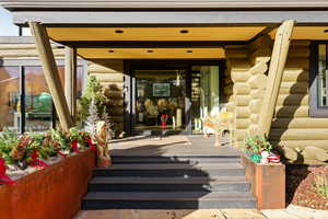 Property entrance with log siding and a porch
