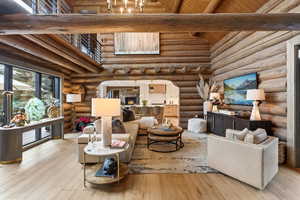 Living room with high vaulted ceiling, arched walkways, hardwood / wood-style floors, a wooden ceiling with exposed beams, and rustic walls