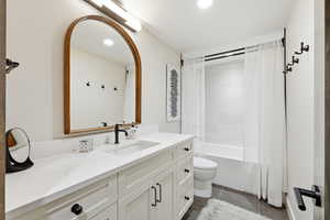 Bathroom with vanity, shower / tub combo, dark tile patterned floors, and recessed lighting