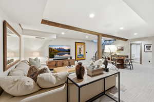 Carpeted living room with beam ceiling, stairway, and recessed lighting