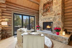 Living room featuring log walls, a wood ceiling with exposed beams, a fireplace, hardwood / wood-style floors, and high vaulted ceiling