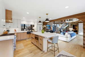 Kitchen featuring log walls, light brown cabinetry, a kitchen bar, decorative light fixtures, and light wood-style flooring