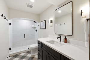 Full bathroom featuring dark flooring, vanity, and a shower stall