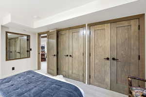 Carpeted bedroom featuring multiple closets and baseboards