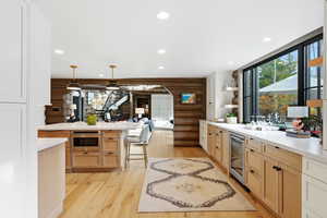 Kitchen featuring rustic walls, light brown cabinetry, pendant lighting, light wood-style flooring, and a breakfast bar area