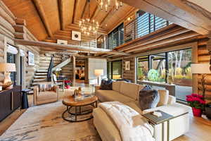 Living area with high vaulted ceiling, stairway, wood-type flooring, rustic walls, and a wooden ceiling with exposed beams