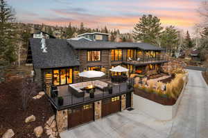 View of front facade featuring log siding, roof with shingles, concrete driveway, a patio, and an outdoor living space with a fire pit