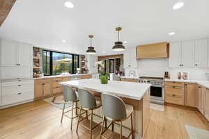 Kitchen featuring light brown cabinets, stainless steel stove, open shelves, pendant lighting, and recessed lighting