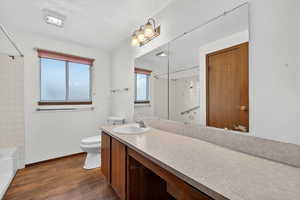 Bathroom with dark wood-style flooring, vanity, and shower / washtub combination