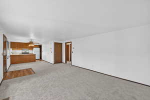 Unfurnished living room with light colored carpet and a ceiling fan