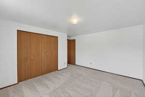 Unfurnished bedroom featuring a closet, carpet floors, and a textured ceiling