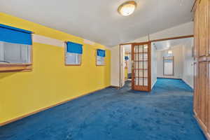 Empty room with lofted ceiling, carpet, and french doors