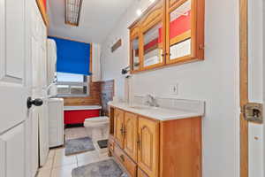 Bathroom with a bathtub, vanity, light tile patterned floors, and washer / dryer