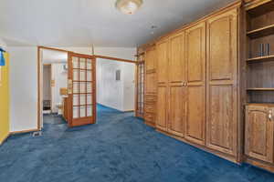 Unfurnished bedroom featuring french doors, vaulted ceiling, dark carpet, and a closet