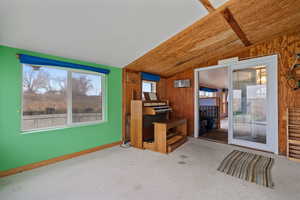 Carpeted living room with vaulted ceiling, wooden walls, and wooden ceiling