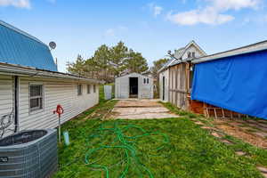 View of grassy yard featuring a deck and a storage unit