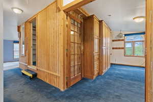 Corridor with dark carpet and lofted ceiling