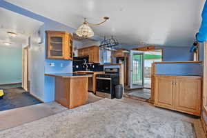 Kitchen featuring brown cabinetry, appliances with stainless steel finishes, open shelves, glass insert cabinets, and light colored carpet
