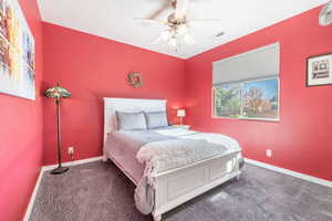 Carpeted bedroom with ceiling fan and baseboards