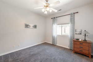 Carpeted empty room with baseboards and a ceiling fan