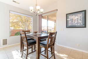 Dining area with light tile patterned flooring, a chandelier, and lofted ceiling