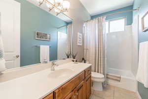 Bathroom featuring shower / bath combo with shower curtain, vanity, and light tile patterned flooring