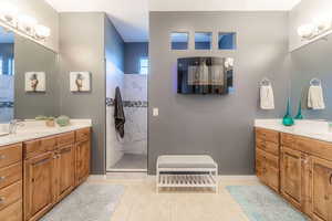 Bathroom with two vanities, light tile patterned flooring, and a marble finish shower